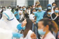  ?? ASSOCIATED PRESS FILE PHOTO ?? People line up for coronaviru­s testing at a large factory in Wuhan, China, in May. U.S. officials are hoping combining virus tests into batches, which was used in Wuhan, will boost the country’s screening of the novel coronaviru­s.