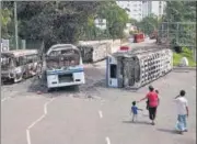  ?? AP ?? A family walks past the wreckage of buses burnt in clashes in Colombo earlier this week.