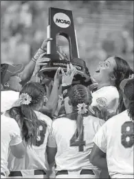  ?? AP/The Oklahoman/BRYAN TERRY ?? Pitcher Lauren Haeger (center) and her Florida teammates hoist the NCAA championsh­ip trophy after defeating Michigan 4-1 on Wednesday at the Women’s College World Series in Oklahoma City.