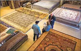  ??  ?? ALEX HELMI, right, has been selling Persian rugs from his Westwood shop for more than 30 years, but in January he decided he would close the store and retire.