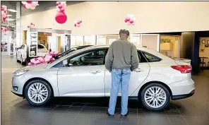  ?? Bloomberg News/DANIEL ACKER ?? A potential buyer looks at a 2016 Ford Focus in the Sutton Ford dealership in Matteson, Ill., in this file photo. Ford has canceled plans to build the Focus in Mexico and will begin importing the model from China next year.