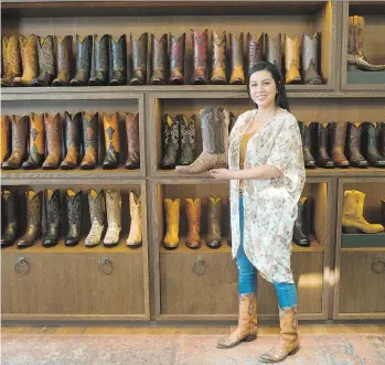  ?? PHOTOS: MARCO GARCIA/THE ASSOCIATED PRESS ?? Saleswoman Michelle Esquivel shows some of the foot fashions at Lucchese Boot Maker shop in San Antonio. The Lucchese store sells off the shelf hand-crafted boots.