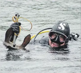  ??  ?? Scuba diver Quinton Smith surfaces with the vintage anchor lost by a solar boat operator in the Otonabee River last month.