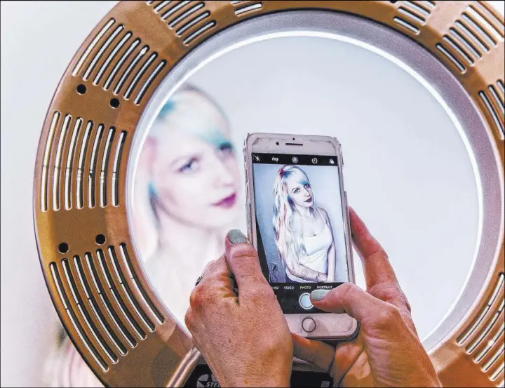  ?? Benjamin Hager Las Vegas Review-Journal @benjaminhp­hoto ?? Las Vegas native and hairstylis­t Shelley Gregory frames client Jessica Pauli through a ring light as she photograph­s her at Atelier by Square Salon.