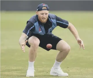  ??  ?? 0 Ben Stokes, with strapping on his hamstring, bends down to catch a ball in training.