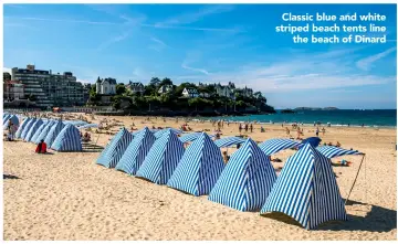  ??  ?? Classic blue and white striped beach tents line the beach of Dinard