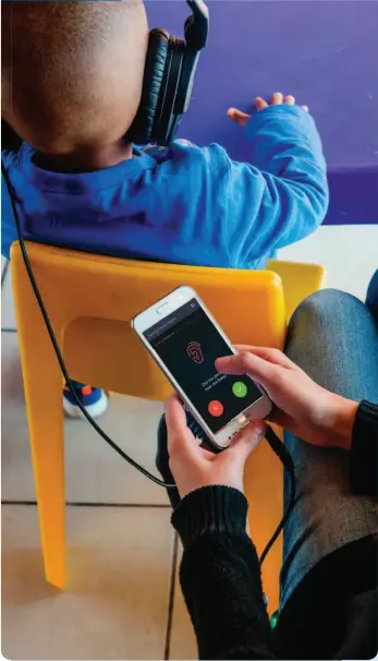  ??  ?? Left: A standardis­ed smartphone is used to administer the hearX test. The automated software presents the tones to the patient, while the person conducting the test indicates whether the patient heard the sound in their left or right ear.