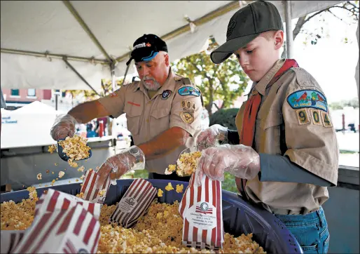  ?? KYLE TELECHAN/POST-TRIBUNE PHOTOS ?? Boy Scout Troop 904 member Carter Kallio, 12, and troop leader Dale Kroeger bag popcorn during the Valparaiso Popcorn Fest.