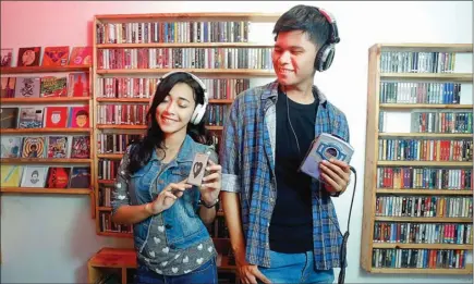  ?? ARYA DHITYA/JAWA POS ?? PAMOR NAIK: Penggemar rilisan fisik musik mencoba kaset lawas di Cempaka Music Store. Saat ini toko-toko musik mandiri kembali marak. compact disc