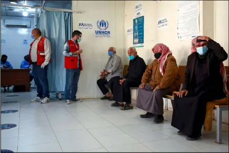  ??  ?? لاجئون سوريون ينتظرون دورهم لتلقي اللقاح ضد كورونا في مركز طبي في مخيم الزعتري شمال العاصمة عمان