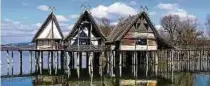  ?? FOTO: FELIX K STLE/DPA ?? Drei Häuser des Pfahlbaumu­seums spiegeln sich im Bodensee wider.