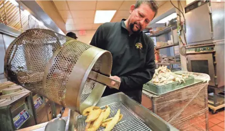  ?? SARAH KLOEPPING/USA TODAY NETWORK-WISCONSIN ?? John Smits, owner of Redwood Inn, takes out a serving of perch from the fryer on Feb. 18, 2022, in Ledgeview, Wis.