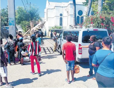  ?? PHOTO BY ANDRE WILLIAMS ?? Kingston Parish Church looms large in the background as onlookers gather at Temple Lane in Kingston where a newborn was discovered in the trash on Monday.