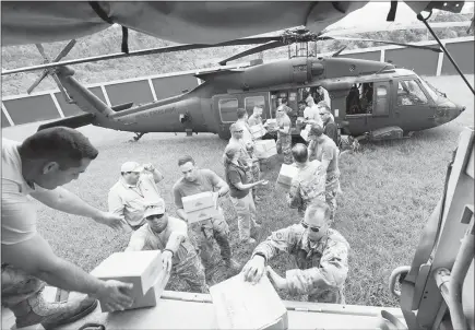  ?? DEPARTMENT OF DEFENSE VIA THE NEW YORK TIMES ?? U.S. Army Lt. Gen. Jeff Buchanan, the commander of Joint Task Force Puerto Rico, and soldiers from the Puerto Rico National Guard, unload a helicopter carrying relief supplies on Wednesday in Jayuya, Puerto Rico. President Donald Trump suggested again...