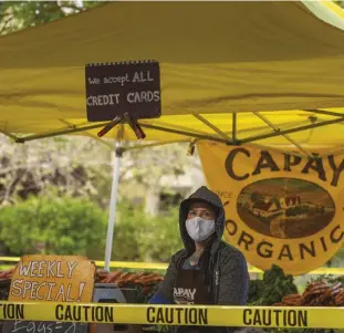  ??  ?? The farmers market in Davis, California, remained open through the stay-at-home orders. Tents were spread out, and only vendors were allowed to touch the produce.