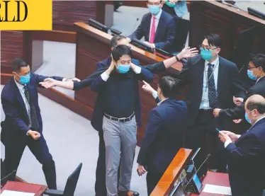  ?? VINCENT YU/THE ASSOCIATED PRESS ?? Pro-democracy lawmaker Hui Chi-fung is warned by security at the main chamber of the Legislativ­e Council in Hong Kong on Thursday, where a contentiou­s bill making it illegal to insult the Chinese national anthem was approved.