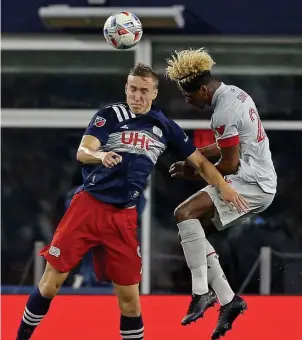  ?? MATT STONE / HERALD STAFF FILE ?? NEXT MAN UP: Revolution striker Adam Buska, left, heads the ball as Toronto FC defender Luke Singh battles for position during their June 8 match. Buska is out of tonight’s lineup against New York City FC as he’s playing in World Cup qualifiers for his native Poland.