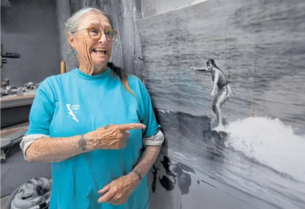  ?? KARL MONDON/STAFF ?? Surfing pioneer Rosemari Reimers Rice gets a kick out of this image of herself surfing in 1962. The photo hangs in the workshop of her late husband, surfboard shaper Johnny Rice.