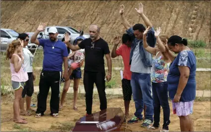  ??  ?? Family members pray during the funeral of a relative who was a prisoner prison in Altamaria, Para state, Brazil, on Wednesday. AP PHOTO/RAIMUNDO PACCO