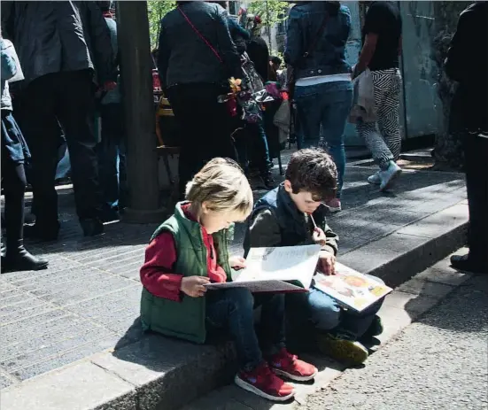  ?? KIM MANRESA ?? Lectura per a tothom. Dos nens, en Tomás i l’Álex, llegint a la Rambla de Barcelona en la jornada de Sant Jordi d’ahir