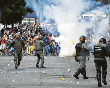  ?? Yuri Cortez / AFP / Getty Images ?? Riot police clash with opposition demonstrat­ors last month in Caracas, Venezuela. The U.S. government is working to remove President Nicolás Maduro with sanctions.
