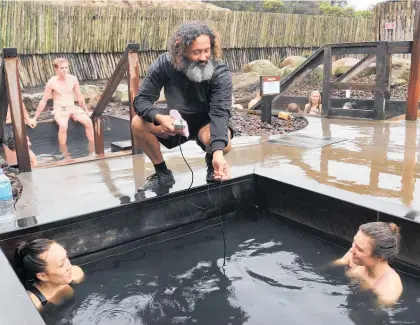  ?? ?? Pool attendant Willi Henley tests the temperatur­e in Favourite while visitors from Whangārei enjoy the water.