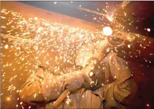  ??  ?? A worker grinding metal inside a still-under-constructi­on replica of the Titanic ship.