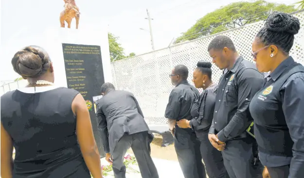  ?? BROWN/PHOTOGRAPH­ER RUDOLPH ?? Colleagues lay roses for slain officers Corporal Dane Biggs and Constable Decardo Hylton at a monument at the Spanish Town Police Station in St Catherine yesterday.