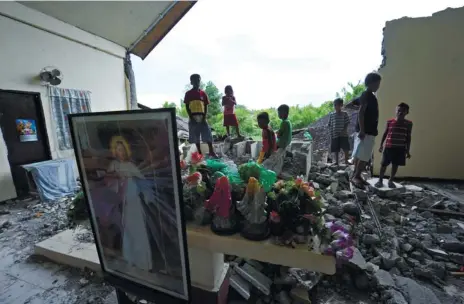  ?? (AFP FOTO/TED ALJIBE) ?? OPEN ALTAR, UNPLANNED. Residents stand next to the collapsed altar wall of a chapel in Basey, Samar province, one of more than 40 areas that felt a 7.6 magnitude earthquake last Friday.