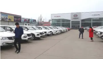  ?? — Reuters photo ?? Dealers and customers are seen next to cars at a SAIC-GM-Wuling Baojun dealership in Pingdingsh­an, Henan province, China.