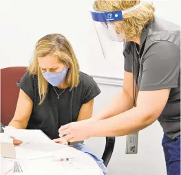  ??  ?? Susan Streaker, a school nurse at Point Pleasant Elementary and Glendale Elementary schools, reviews the ingredient­s of Moderna vaccine for allergies with Disease Prevention and Management Deputy Director, Jennifer Schneider.