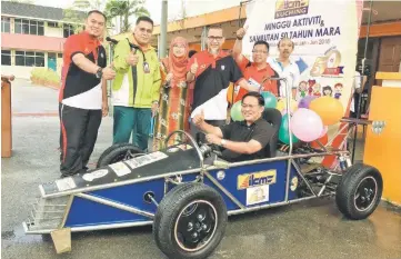  ??  ?? Abdul Rahman sits inside a Formula car built by students of IKM while others show their approval.