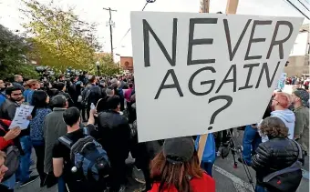 ?? AP ?? A person holds a sign at a protest near the Jewish Community Centre in the Squirrel Hill neighbourh­ood of Pittsburgh, during the funeral of Tree of Life Synagogue massacre victim Dr Jerry Rabinowitz.