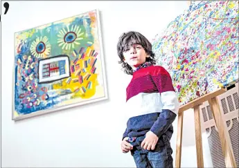  ??  ?? Mikail poses in front of a print edition of his ‘Champi’ painting (right) and his painting ‘Sonnenblum­e Mensch’ (Sunflower Man) (left) prior to the opening of his ‘Manus 11’ exhibition in Berlin.