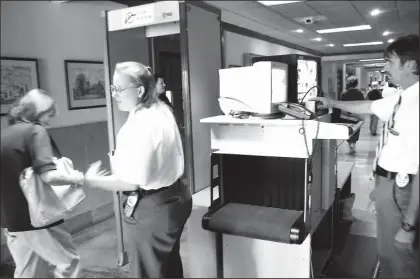  ?? Staff Photo by Sean McRae Loftin ?? Valerie Lewis, left, of Walden Security makes visitors to the Hamilton County Courthouse pass through a metal detector while Rick Hudson, right, checks bags using an X-ray machine.