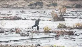  ?? Brian van der Brug Los Angeles Times ?? A YOUNG WOMAN runs through the debris-choked Santa Clara River channel at Sand Canyon Road. A f lash-f lood warning is in effect for the area.