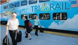  ?? MIKE STOCKER/STAFF PHOTOGRAPH­ER ?? Riders with luggage at the Hialeah Market Station leave the train and head to a bus for the airport. Tri-Rail’s Miami Airport station won’t open until late March or early April.