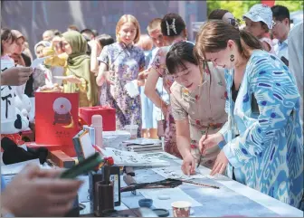  ?? GEORGIY NAMAZOV / XINHUA ?? Visitors try out Chinese calligraph­y at a park in Tashkent, Uzbekistan, on May 27.