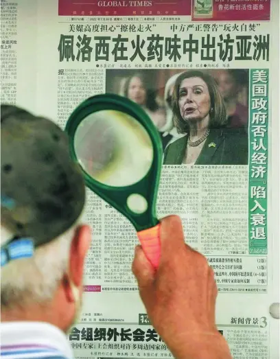  ?? AP ?? Un hombre lee con una lupa una noticia sobre la visita de Pelosi a Taiwán