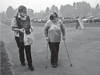  ??  ?? Mary Thomson, right, of Phoenix, Ore., gets assistance from Salvation Army officer Tawnya Stumpf at an evacuation center at the Jackson County Fairground­s on Saturday in Central Point, Ore.