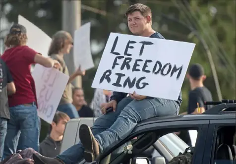  ?? Pam Panchak/Post-Gazette ?? Joshua May, 17, a junior at Hempfield Area High School, sits on the roof of a car during a rally Tuesday in front of the school protesting the statewide policy requiring masks to be worn in schools.