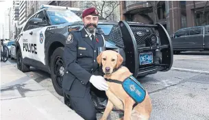  ?? TORONTO POLICE SERVICE ?? Const. Paul Breeze poses with his service dog, Scarlett, after participat­ing in a Remembranc­e Day ceremony. Breeze is Toronto’s first active police officer to work with a service dog.