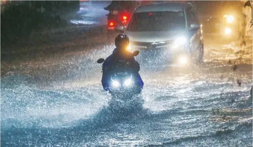  ?? RIANA SETIAWAN/JAWA POS ?? IMBAS HUJAN DERAS: Pengendara sepeda motor menerobos genangan di Jalan Lontar Senin malam (28/12). Hujan lebat mengakibat­kan genangan di sejumlah ruas di Surabaya Barat.