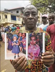  ?? MANIKA KAMARA / ASSOCIATED PRESS ?? Amara Kallon holds photos of his daughter Hawa outside Connaught hospital morgue in Freetown, Sierra Leone, on Wednesday. Hawa was killed in Monday’s flooding and mudslides.