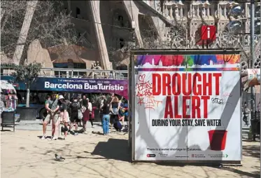  ?? — AFP ?? Tourists near the famous La Sagrada Familia basilica in Barcelona, Spain, where a drought alert banner is on display.