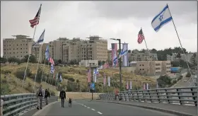  ?? AP/ARIEL SCHALIT ?? Security officers on Sunday walk the road leading to the U.S. Embassy compound in Jerusalem.