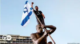  ??  ?? Israeli artist Itay Zalait atop his statue