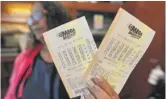  ?? MIKE STEWART/AP ?? $1.6 BILLION: A shop employee in Atlanta on Monday holds Mega Millions lottery tickets. Tuesday night’s drawing is expected to be the largest lottery jackpot in U.S. history.