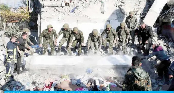  ??  ?? THUMANE, Albania: Emergency workers clear debris at a damaged building 34 km northwest of the capital Tirana yesterday after an earthquake hit Albania. — AFP