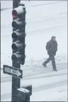  ?? Associated Press photo ?? A pedestrian walks as snow falls Sunday in downtown Kansas City, Mo.